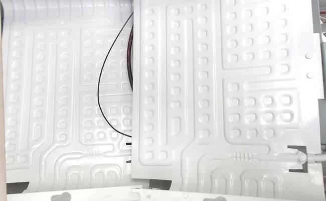 Một người thợ kỹ thuật đang cẩn thận vệ sinh bên trong một máy làm đá viên 60kg. Anh ấy đang sử dụng khăn sạch và dung dịch tẩy rửa chuyên dụng. Ánh sáng phòng bếp công nghiệp sạch sẽ.